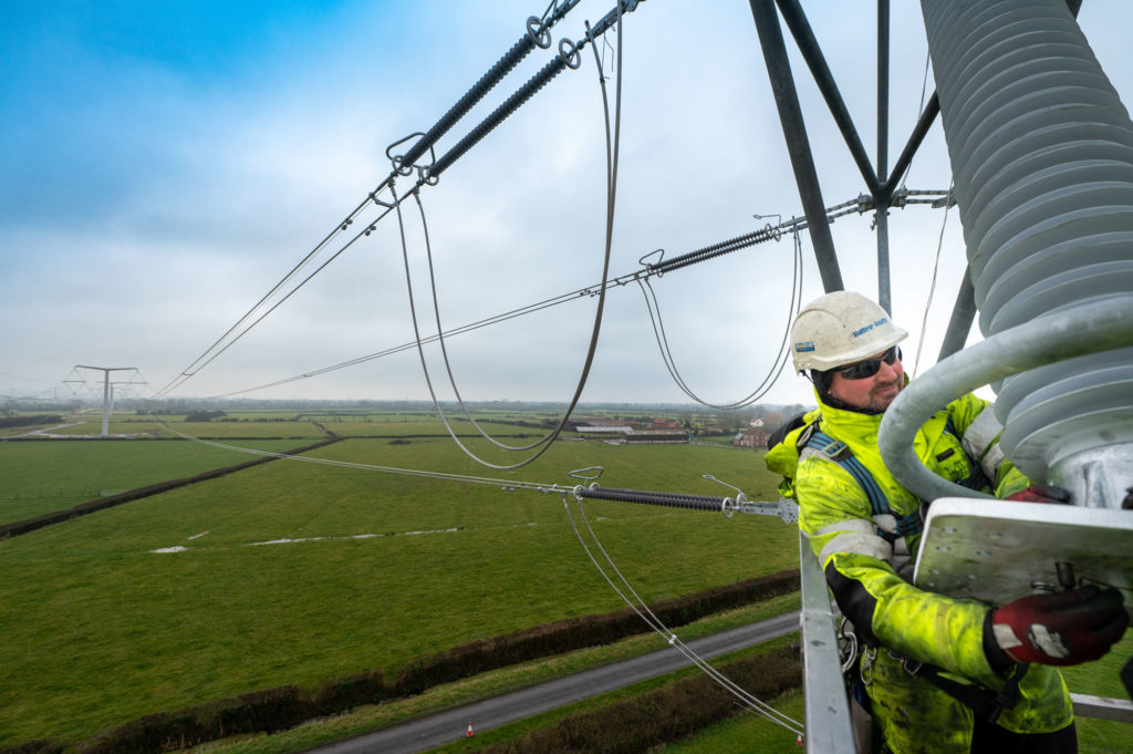 Infrastructure Photography of worker on T pylon in North Somerset
